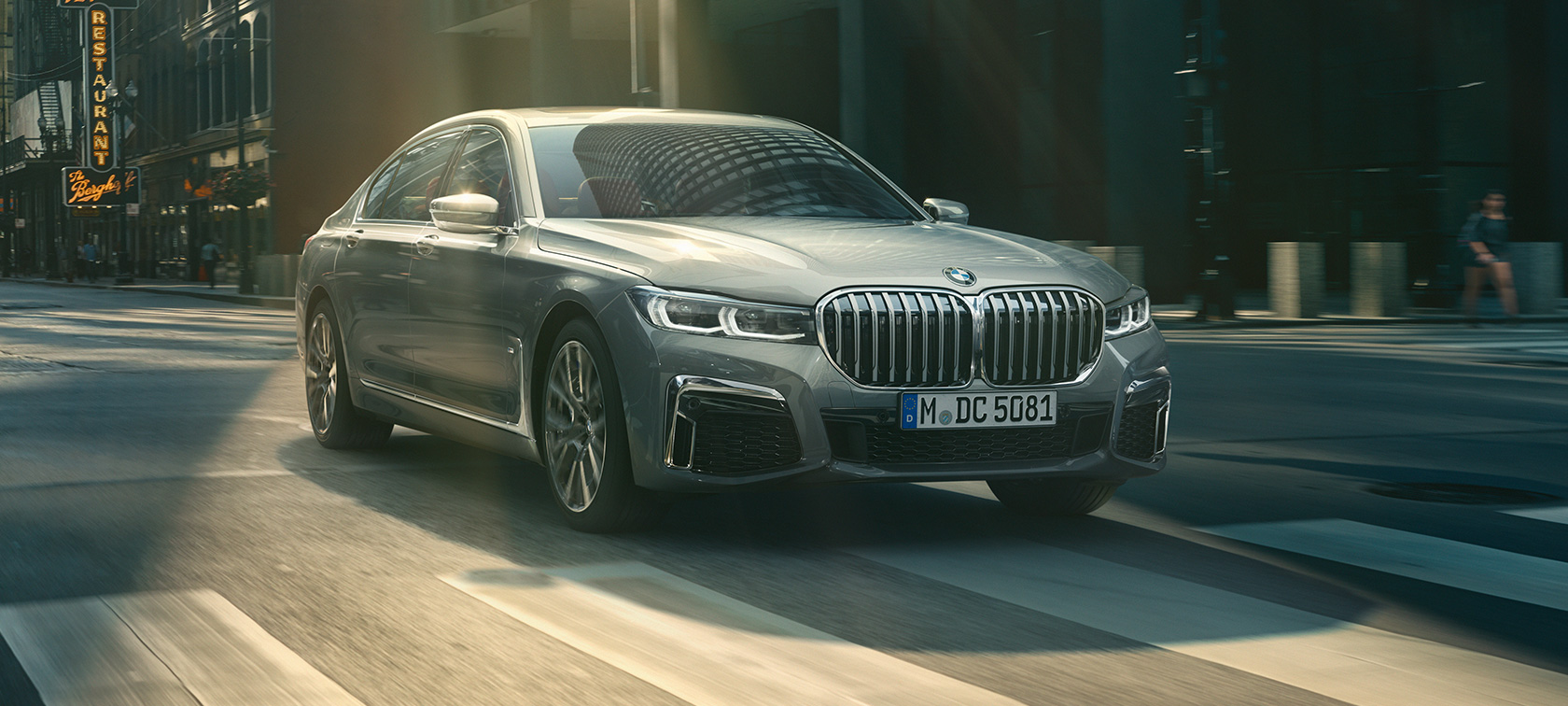Grey BMW 7 Series Sedan driving, three-quarter front view Grey BMW 7 Series Sedan drives through the urban setting in the three-quarter front view