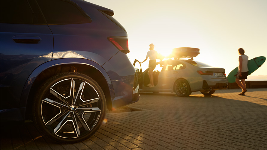 BMW Wheels and Tyre Service BMW X1 U11 with two people on BMW vehicle in background with sun